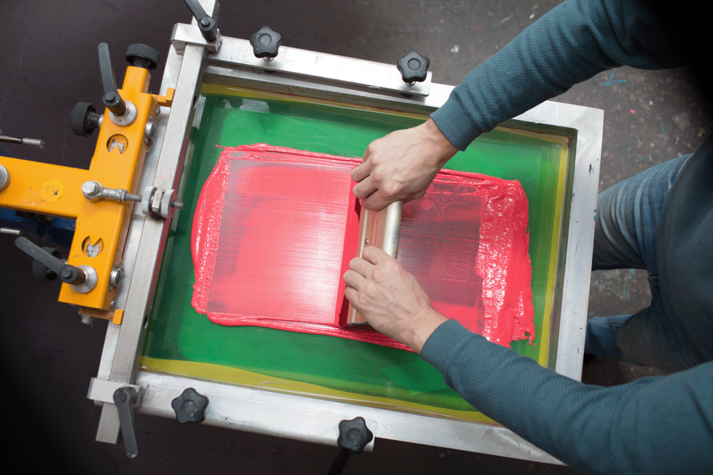 Screen printing ink application from screen to garment printing.